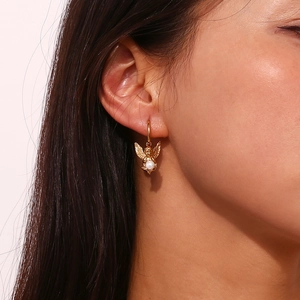 Close-up of vintage angel wing earrings in 18K gold finish with white pearl accents