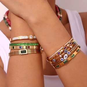 Close-up of stacked 18K gold plated bead bracelets featuring colorful zircon stones