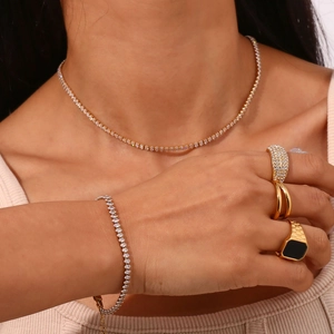 Parure de bijoux tennis dorée élégante comprenant collier, bracelet et bagues sur modèle