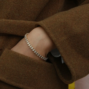 Vue détaillée d'un bracelet de tennis doré avec zircons ovales sur une manche de manteau
