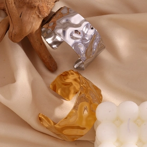 Macro detail of gold and silver hammered metal cuff bracelets on minimalist fabric
