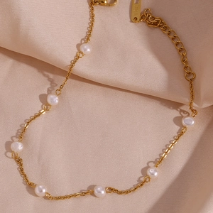 Close-up of 18K gold chain anklet with freshwater pearls on elegant champagne satin