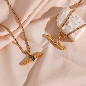 Detailansicht der goldenen T-Bar Anhänger mit Zirkonia auf elegantem rosa Satin