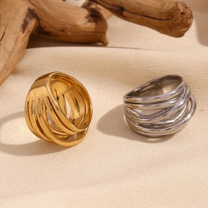 Detailed shot of woven gold and silver stainless steel rings on a minimalist beige fabric