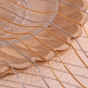 Detail view of twisted gold and silver stainless steel chain necklaces on ceramic tray