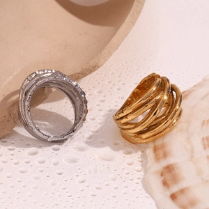 Detail of wide multi-layer intertwined rings in gold and silver finish with water drops