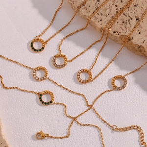 Detail goldener gedrehter Kreisanhänger mit grünen Steinen, Perlen und Strass an feinen Ketten
