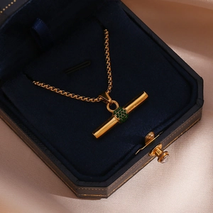 Detail der 18K vergoldeten T-Bar-Kette mit grünem Stein in einer blauen Box