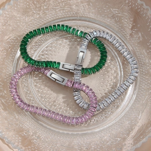 Detail view of emerald, pink, and white cubic zirconia tennis bracelets on glass tray
