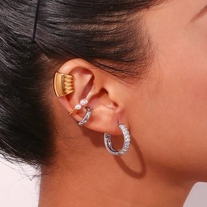 Detailed close-up showing stacked 18K gold and silver earrings with pearls and zircon stones