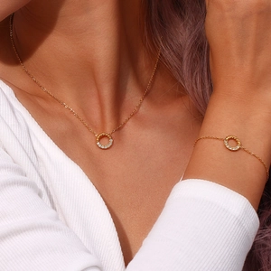Detailansicht eines goldfarbenen Schmucksets mit gedrehtem Ring und funkelnden Kristallen