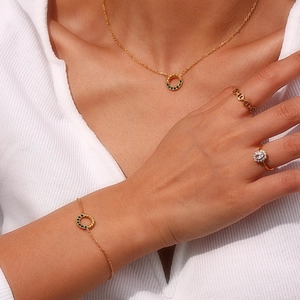 Detailaufnahme von Goldkette und Armband mit grünen Smaragdanhängern im Set