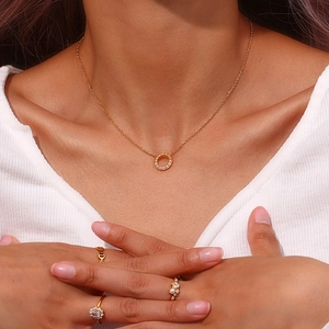 Detailansicht einer Frau mit goldener Kordelkette und mehreren luxuriösen Ringen am Set
