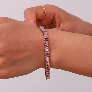 Detail van roze rechthoekige zirkoon tennisarmband met goudlaagje om de pols