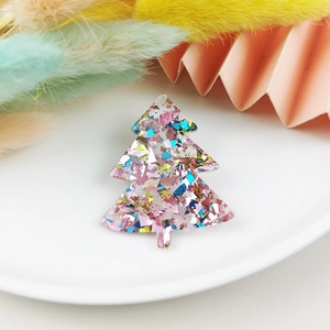 Detail view of a clear acrylic Christmas tree pendant with shimmering pink glitter flakes