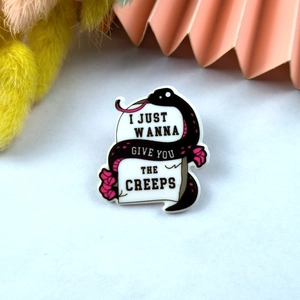Gothic acrylic pin featuring a black snake and pink flowers on a white tombstone