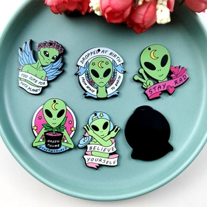 Grüne Alien-Emaille-Pins-Set mit motivierenden Sprüchen auf einem hellblauen Teller
