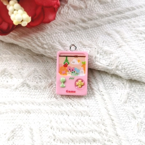 Macro shot of pink resin handheld game console charm with cute cartoon screen details