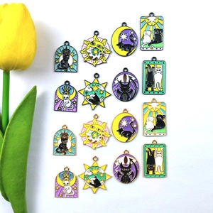 Macro shot of 16 assorted black cat tarot enamel charms for DIY jewelry making with a flower