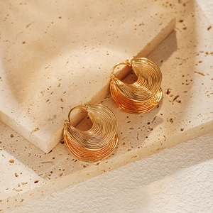 Textured gold-plated irregular earrings with tiered crescent design on stone background