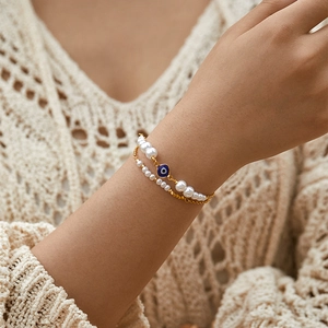 Dettaglio dell'occhio di Allah placcato oro su un bracciale a doppio filo di perle