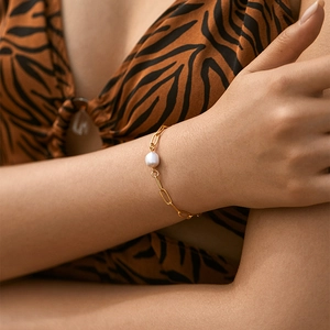Dettaglio di un bracciale a catena con una perla d'acqua dolce naturale su un polso