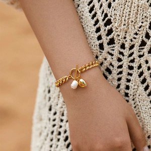 Bracciale in ottone placcato oro 18K con perla barocca e ciondolo a cuore sul polso
