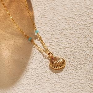 Gros plan détaillé d'un pendentif coquillage plaqué or avec des perles bleu turquoise