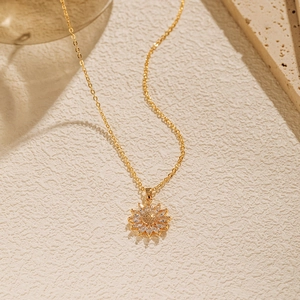 Détail macro du pendentif tournesol avec pétales en zircon et centre doré mat élégant