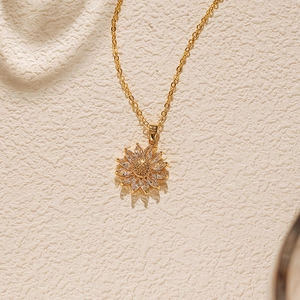 Détail du collier tournesol doré avec zircons étincelants et fine chaîne maille jante