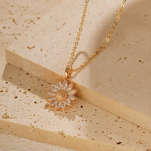 Gros plan du collier pendentif tournesol doré avec zircons sur un support en pierre