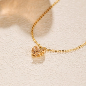 Détail macro d'un collier pendentif coeur doré orné de micro-incrustations latérales