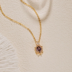 Détail du collier tortue dorée avec pierre violette et zircons sur corail blanc décor