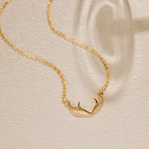 Détail d'un collier plaqué or avec un pendentif en forme de bois de cerf serti de zircons
