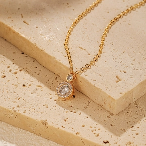 Détail macro du collier plaqué or avec pendentif en zircon rond sur pierre beige