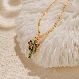 Détail macro du collier cactus doré avec cristaux violets et verts sur corail