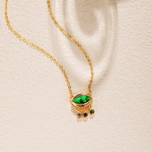 Détail du collier doré vintage avec pierre marquise verte et gemmes colorées