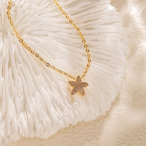 Détail du pendentif étoile en zircon sur une chaîne croisée dorée sur corail
