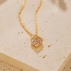 Détail du collier pendentif cœur doré serti de zircons brillants sur un support en pierre