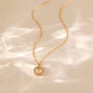 Dettaglio del pendente a fiore placcato oro 18K con zirconi su uno sfondo ondulato