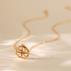 Dettaglio del ciondolo a bussola in oro 18K con pietra rossa e cristalli multicolore