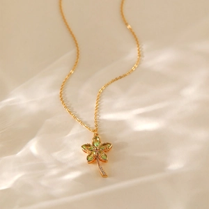 Dettaglio di una collana a fiore dorata con pietre verdi e accenti di diamanti lucidi