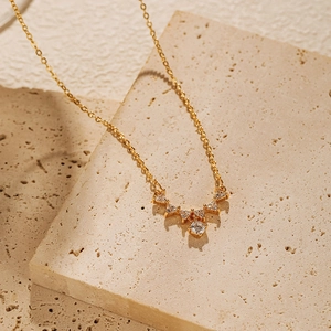 Détail du pendentif en V doré avec zircons brillants posé sur une pierre naturelle