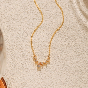 Détail macro du collier plaqué or avec pendentifs en zircon sur fond texturé blanc
