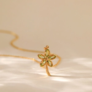 Dettaglio ravvicinato di un ciondolo a fiore in oro 18 carati con cristalli verdi marquise