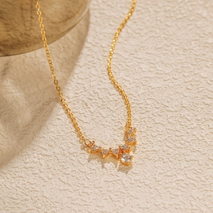 Détail d'un collier doré en forme de V serti de zircons brillants sur fond neutre