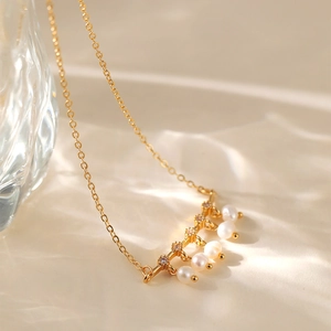 Dettaglio macro di una collana placcata oro 18K con piccoli cristalli e cinque perle