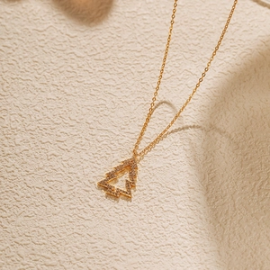 Détail d'un pendentif sapin de Noël doré orné de zircons brillants sertis en pavé