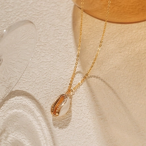 Vue macro d'un collier plaqué or avec pendentif en nacre naturelle sur une chaîne dorée