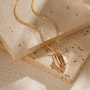 Détail d'un pendentif en coquillage cauri plaqué or sur une surface en pierre